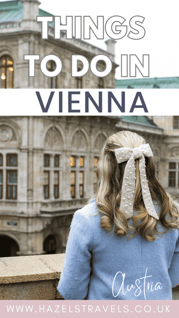Pinterest-style cover image reading “Things to Do in Vienna” in bold white text over a soft grey sky, with a woman in a pale blue coat seen from behind, her blonde hair tied with a large cream bow, looking towards the ornate stone façade and green copper roof of a grand Viennese building, and “Austria” plus hazelstravels.co.uk written at the bottom.