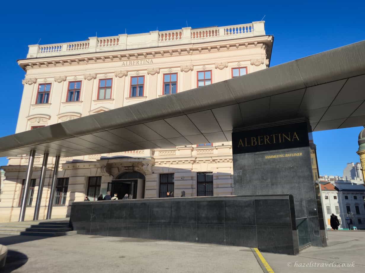 Albertina Museum entrance in Vienna in winter with cream exterior walls and a large grey glass canopy
