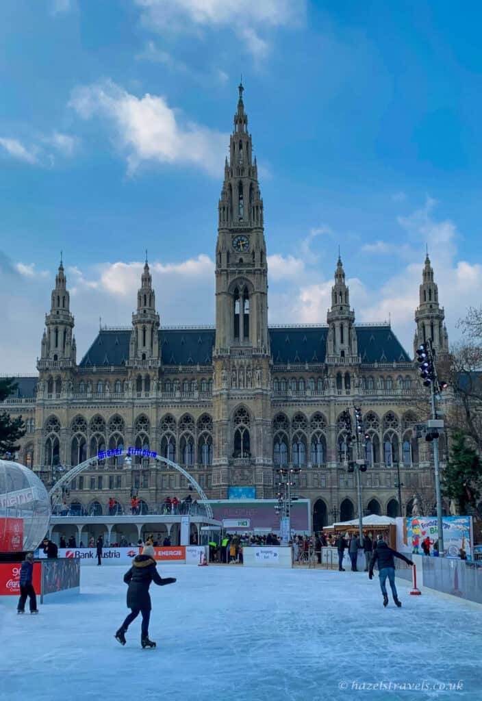 Ice skating rink at Rathausplatz with Vienna City Hall in the background on a clear winter day