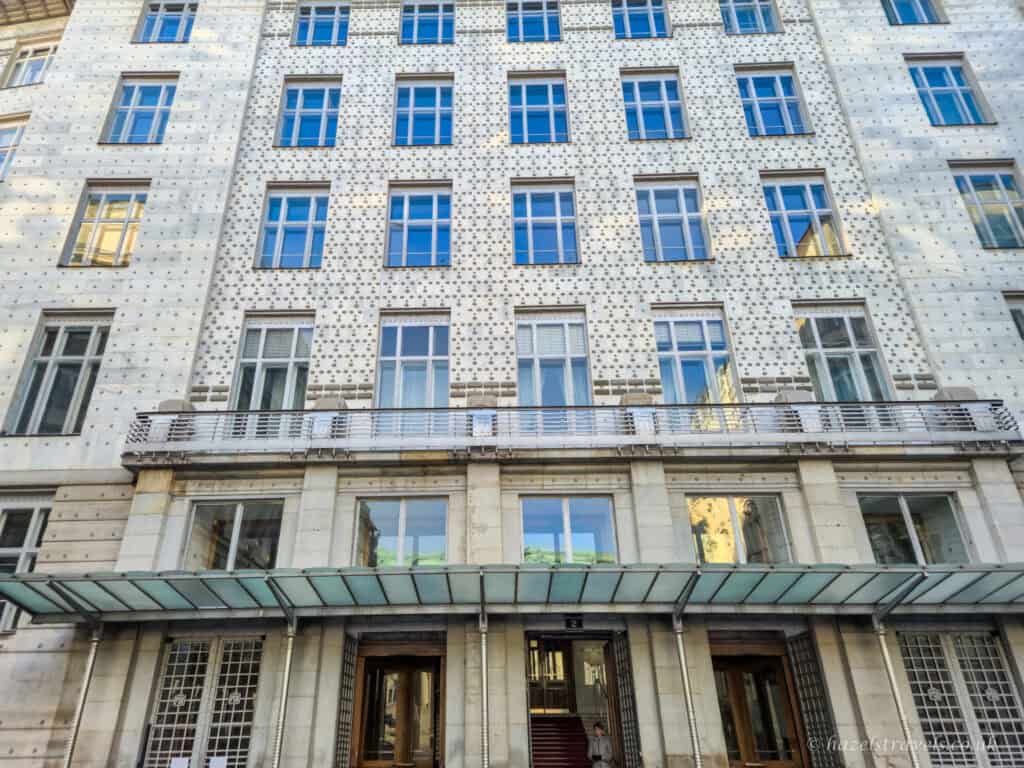 Exterior of the former Austrian Postal Savings Bank building in Vienna, designed by Otto Wagner, with its studded façade, rows of windows, and glass canopy above the entrance.