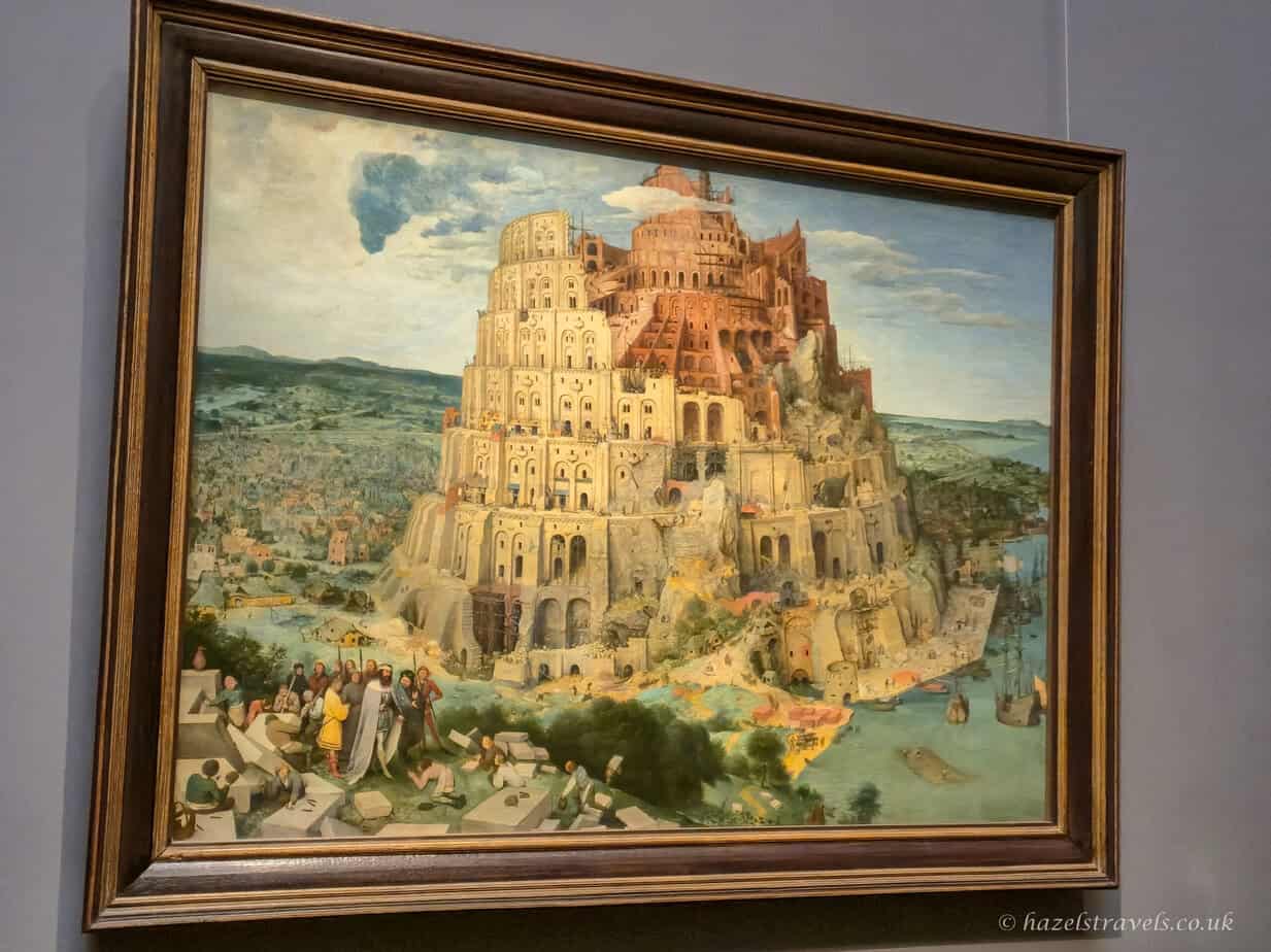 The painting “The Tower of Babel” by Pieter Bruegel the Elder depicting a massive unfinished tower surrounded by a bustling medieval city.