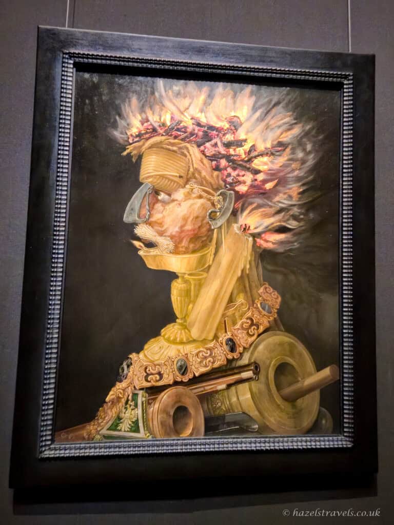 Giuseppe Arcimboldo’s painting “Fire”, a surreal portrait made from flames, burning wood, candles, and metal objects forming a human profile.