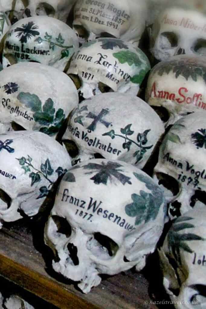 Decorated human skulls with painted names, dates and floral designs displayed in the Hallstatt Charnel House.