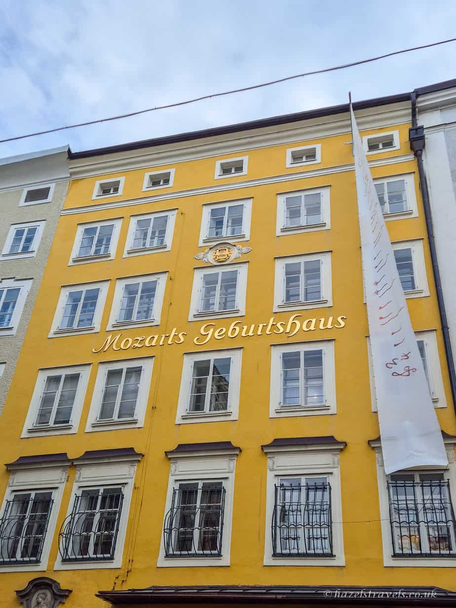 Bright yellow Mozart’s Birthplace building (Mozarts Geburtshaus) in Salzburg’s Old Town with white windows and historic façade on Getreidegasse